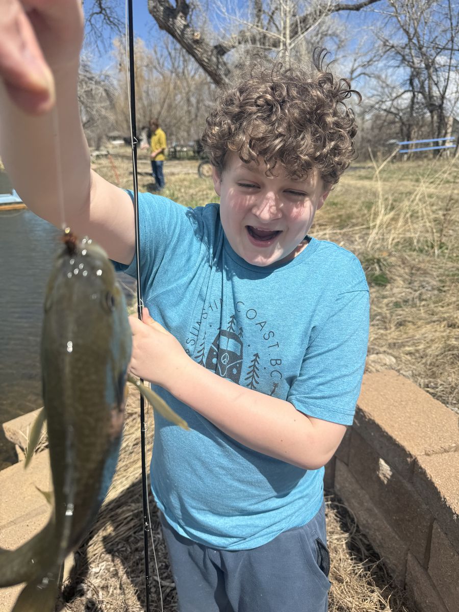 Student holding a bluegill caught on a fly at Temple Grandin School