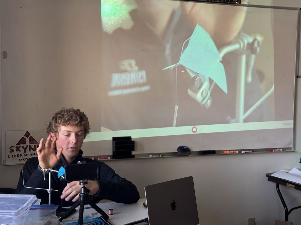 Student tying a fly during class, projected on the whiteboard